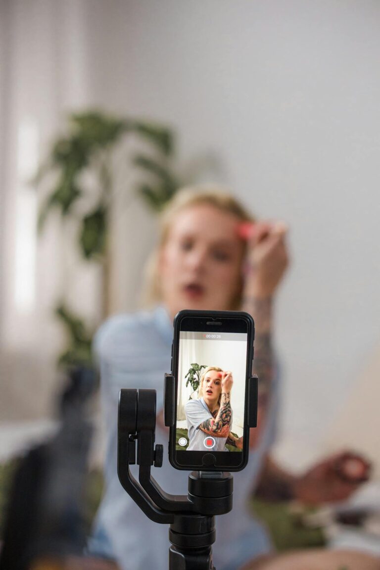 A beauty influencer using a smartphone to film a makeup tutorial at home, emphasizing modern content creation.