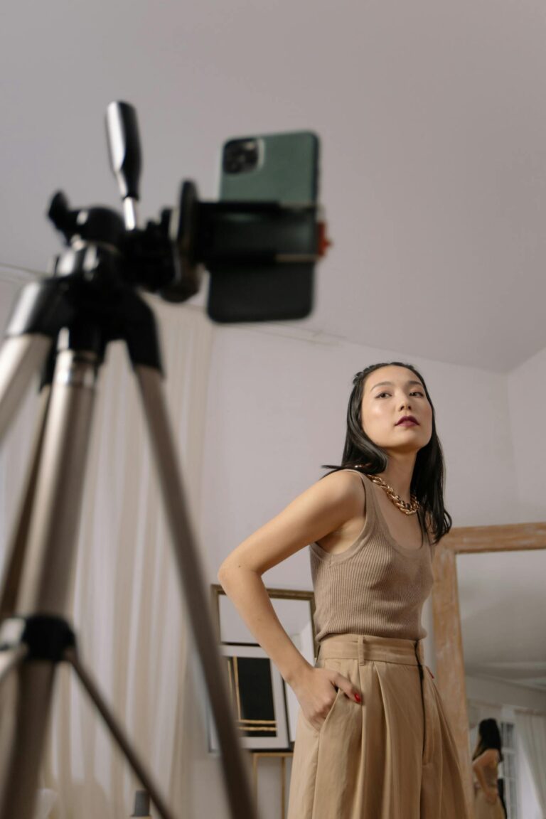 Fashionable Asian woman posing for a vlog indoors, capturing a stylish moment.